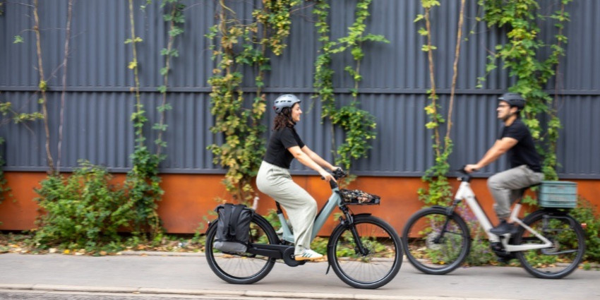 on voit deux personne une femme et un homme sur des vélo electrique de la marque velozen qui sont entrain de se balader dans une ruelle 